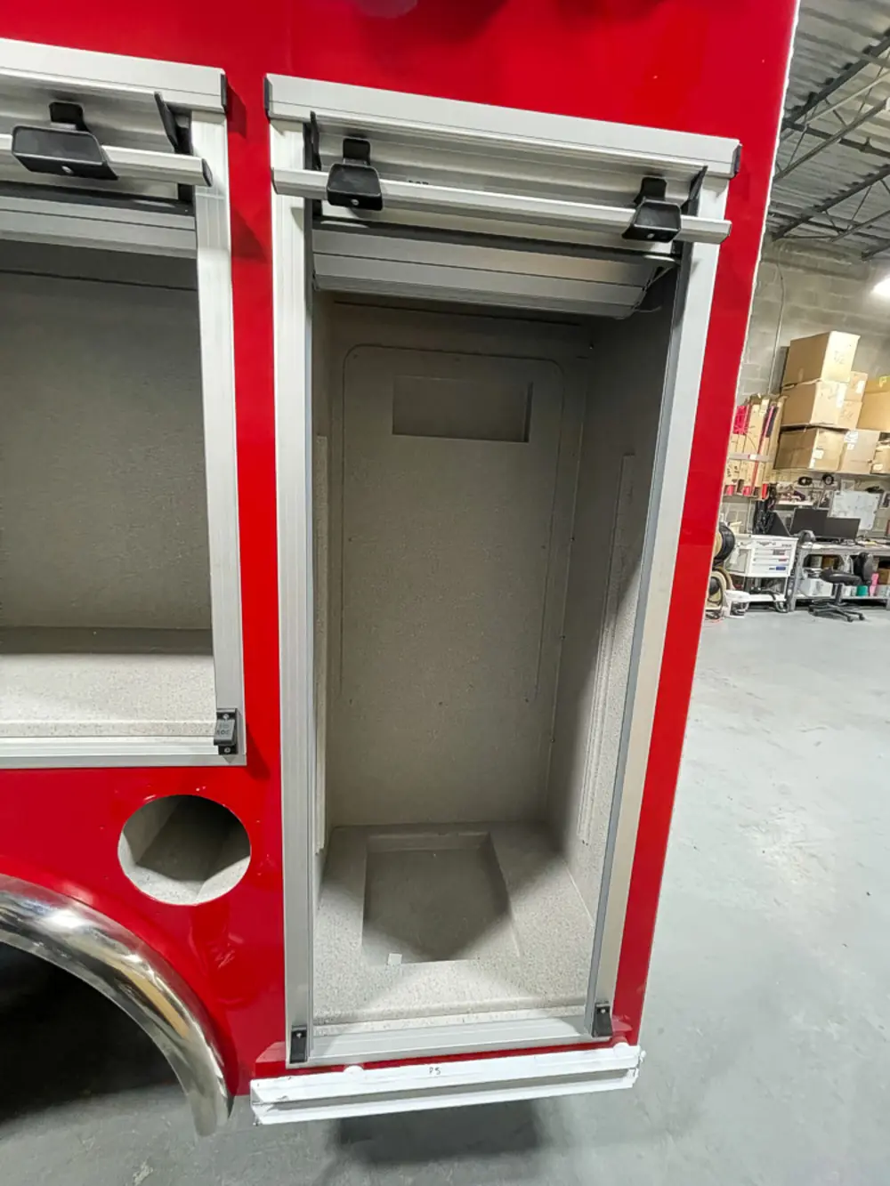Exterior view of small fire truck showing cab, body compartments, and wheel/tire area.